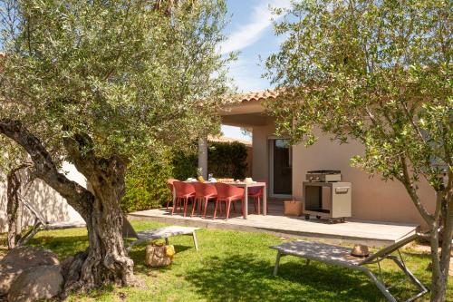 a backyard with a table and chairs under a tree at Résidence Marina Rossa in Porto-Vecchio