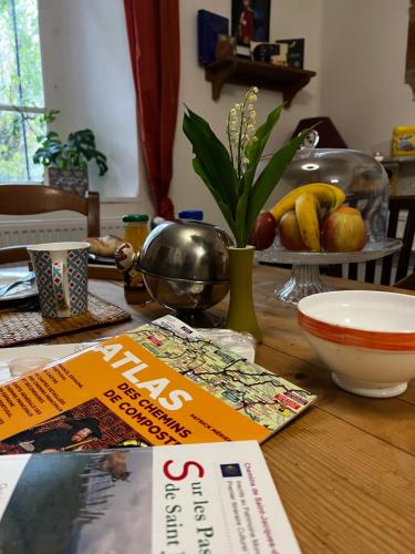 a table with a book and a bowl of fruit at Maison d'Hôtes & Savonnerie de Bonnefon in Saint-Chély-dʼAubrac