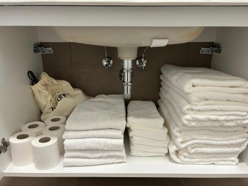 un mucchio di asciugamani seduti su uno scaffale sotto un lavandino di Camere di Bianca a Foligno