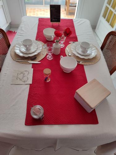 une table blanche avec des serviettes rouges et des assiettes dessus dans l'établissement Gîte et Chambre d'hôte Entre Tilleul et Agrumes, à Vinassan