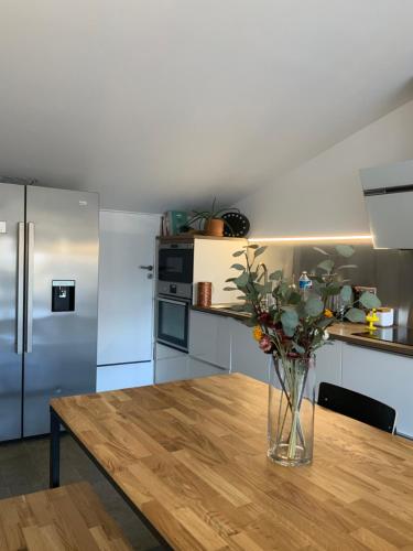 un jarrón de flores en una mesa de madera en una cocina en Riverside duplex penthouse, en Girona