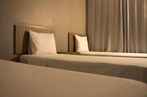 アラグァイーナにあるHotel Ipanemaのホテルルーム内のベッド2台(白い枕付)