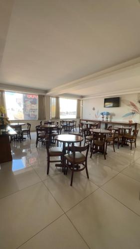 a dining room with tables and chairs and windows at Hotel Ipanema in Araguaína