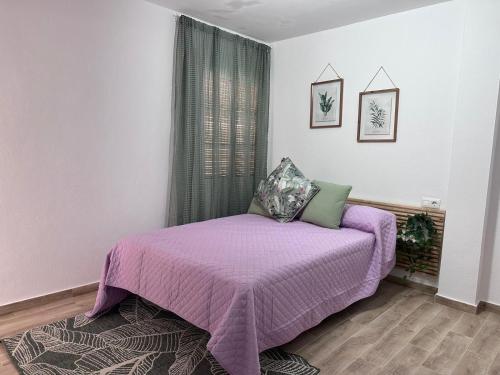 1 dormitorio con cama morada y ventana en Solera, en Jerez de la Frontera