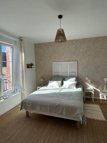une chambre avec un grand lit et une grande fenêtre dans l'établissement Appartement Cote des Isles, à Barneville-Carteret