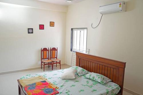 een slaapkamer met een bed en 2 stoelen. bij Green Mango Farmhouse in Chityāl
