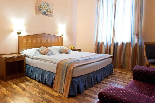a hotel room with a bed and a chair at Kolštejn wellness centrum in Branná