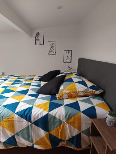 Bett mit bunter Bettdecke und Kissen in der Unterkunft jolie maison neuve - malisone - in Pont-Sainte-Maxence