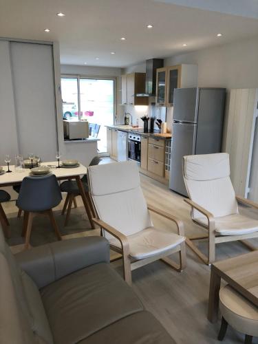 une cuisine avec des chaises blanches et une table et une cuisine avec un réfrigérateur dans l'établissement jolie maison de bourg, à Arvert