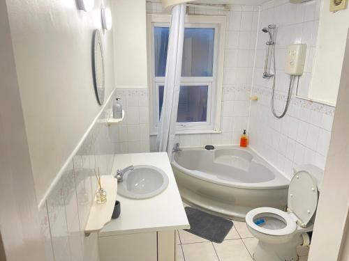 La salle de bains est pourvue d'une baignoire, de toilettes et d'un lavabo. dans l'établissement Hometel Nice Comfy Apartment Can Sleep 10, à Leicester
