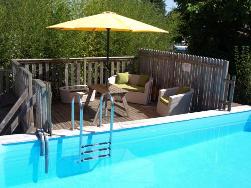 - une terrasse avec une table et un parasol à côté de la piscine dans l'établissement GITE la Rocaille, à Sevremont