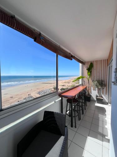 a balcony with a table and chairs and a view of the beach at face mer in Saint-Hilaire-de-Riez