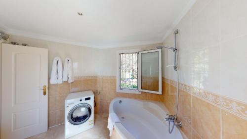 bagno con lavatrice e vasca bianca di Villa Boreal by Oliva Nova a Oliva