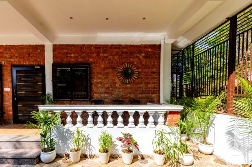 a porch with potted plants and a brick wall at Rahta Villa An elegant 3BR Villa & BBQ Terrace in Dehradun
