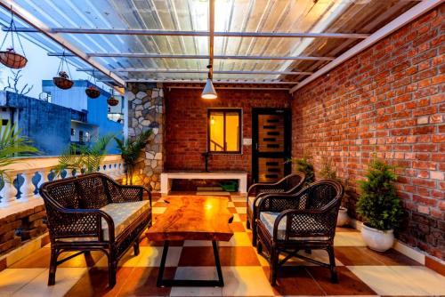a patio with chairs and a table and a brick wall at Rahta Villa An elegant 3BR Villa & BBQ Terrace in Dehradun