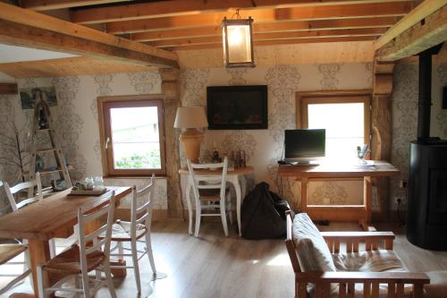 un soggiorno con tavolo, sedie e TV di La CHARETTERIE Gites du Manoir de La Porte a Les Authieux-sur-Calonne