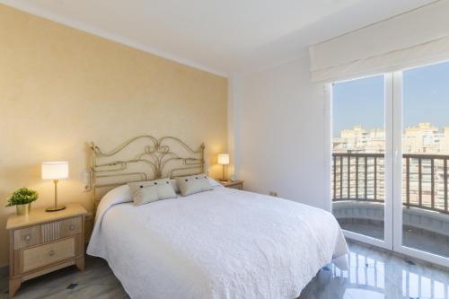 ein Schlafzimmer mit einem weißen Bett und einem großen Fenster in der Unterkunft AG Salinas 9 in Playa de Gandia