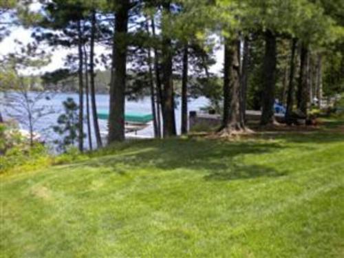 a field of grass with trees and a body of water at Minocqua Lake Condo B10 in Minocqua
