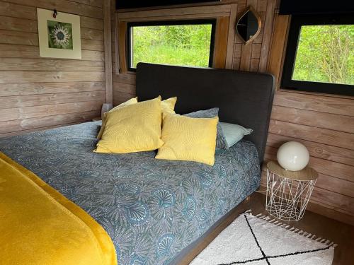 Una cama con almohadas amarillas en una habitación pequeña. en Chalet bois cosy avec piscine Aix nature en Aix-en-Provence