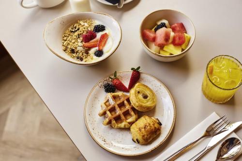 a table with plates of breakfast foods and a bowl of fruit at Novotel Bristol Centre in Bristol
