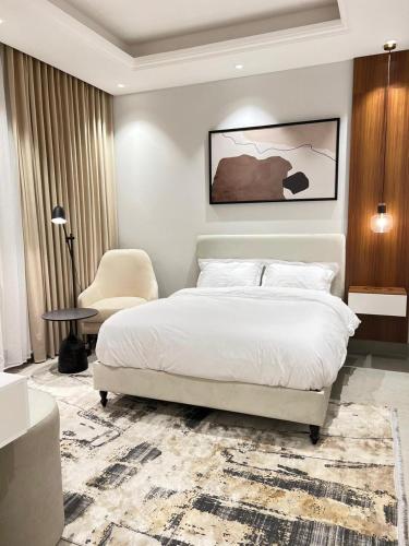 a bedroom with a white bed and a chair at New apartment, two entrances in Riyadh