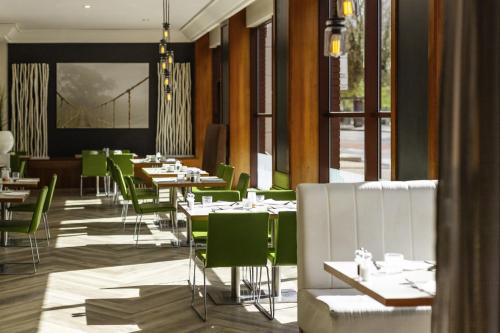 a dining room with tables and green chairs at Novotel Bristol Centre in Bristol