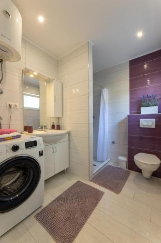 a bathroom with a washing machine and a toilet at Moderni studio in Kaštela