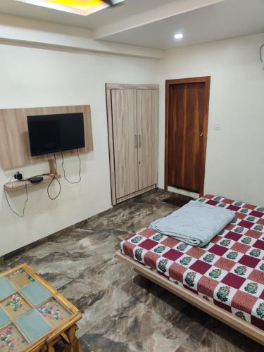 um quarto com uma cama e uma televisão de ecrã plano em PK Lodging em Ulhāsnagar