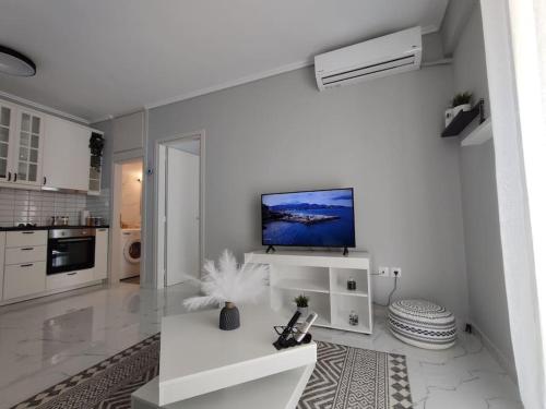 a white living room with a tv on a wall at Amalia's Luxury Apartment in Thessaloniki