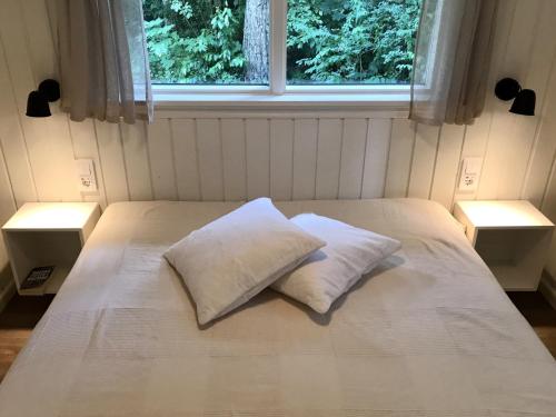 a bed with two pillows on it with a window at Nordic Relax House - Stonehouse in Sjöbo