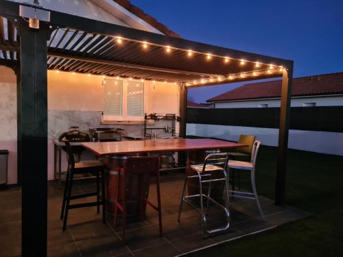 un patio avec une table et des chaises sous une pergola éclairée dans l'établissement maison du bonheur, à Mimizan