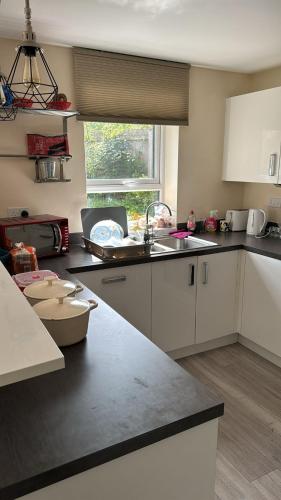 eine Küche mit weißen Schränken, einem Waschbecken und einem Fenster in der Unterkunft Telford Guest House 1 in Telford