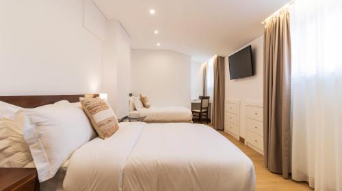 a white bedroom with a bed and a tv at Albergaria Quim Barreiros in Vila Praia de Âncora