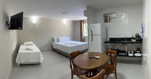 Zimmer mit einem Tisch und einem Bett sowie einer Küche in der Unterkunft Condomínio Pickler in Juquei
