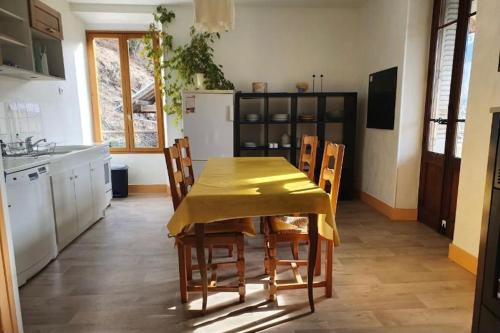 una cocina con una mesa con un mantel amarillo. en Grand appartement terrasse au coeur des Bauges, en Le Châtelard