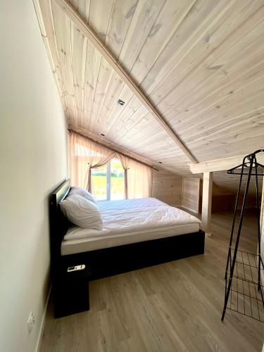 a bed in a small room with a wooden ceiling at Osada Wędkarska 52/10 in Boszkowo