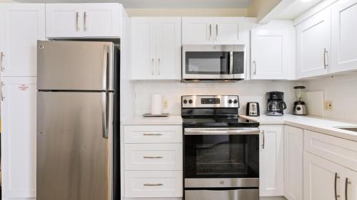 a kitchen with white cabinets and a stainless steel refrigerator at Caloosa Cove Resort in Islamorada