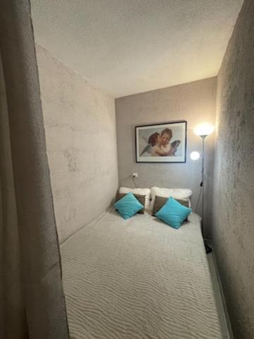 Cette petite chambre comprend un lit avec des oreillers bleus. dans l'établissement JOSEPHINE, à Arcachon