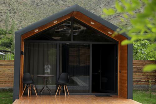 a large black shed with two chairs and a table at NICE HOUSE HOTEL Meghri in Meghri