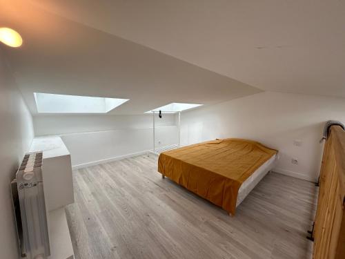 ein Schlafzimmer mit einem Bett in einem weißen Zimmer in der Unterkunft Grand Studio Duplex Stade France in Aubervilliers
