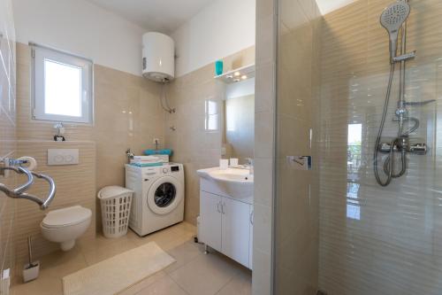 a bathroom with a toilet sink and a washing machine at Apartments Bilopavlović in Kaštela