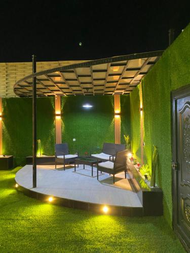 un patio con tavolo, sedie e parete verde di شاليهات لانا لاند نموذج 1 a As Sayl aş Şaghīr