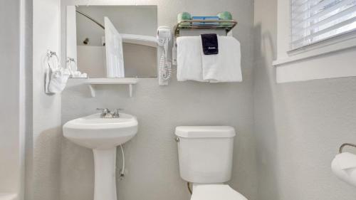 a white bathroom with a toilet and a sink at Crystal Bay Historic Hotel in St Petersburg