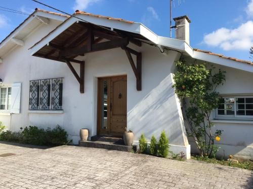 une maison blanche avec une porte en bois dans l'établissement villa spacieuse avec piscine sur cote basque Anglet, à Anglet