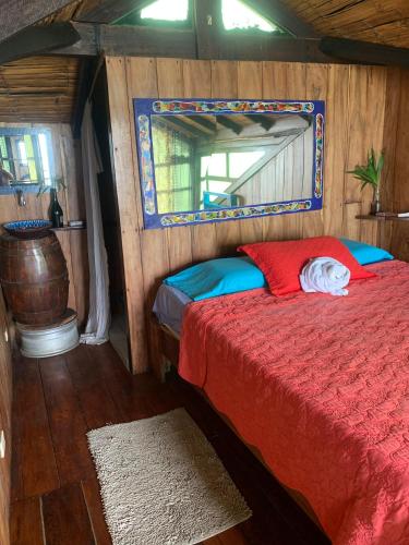 a bedroom with a bed with a red comforter and a mirror at Casa heysol in Bahía de Caráquez