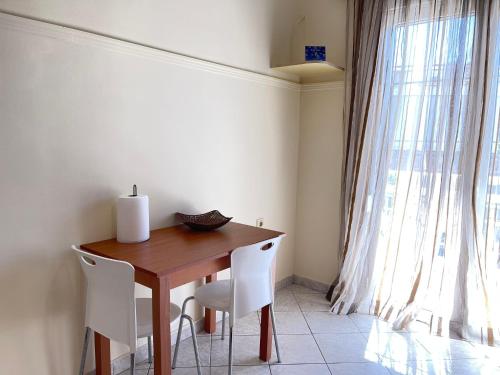 a dining room table with white chairs and a window at Your Home In Elefsis in Eleusis