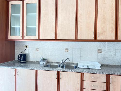 a kitchen counter with a sink and wooden cabinets at Your Home In Elefsis in Eleusis