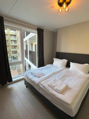 Schlafzimmer mit einem großen weißen Bett und einem großen Fenster in der Unterkunft Moderne 3 Roms leilighet i Oslobukta! in Oslo