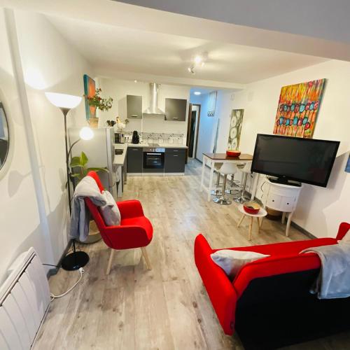 a living room with red chairs and a flat screen tv at Hôte Labyrinthe lit 180 cm salle de bain, petit dej compris in Mirepoix