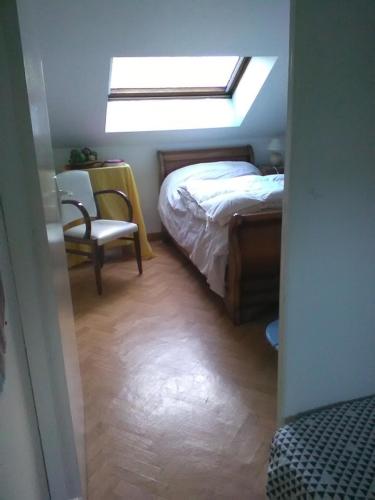 um quarto com uma cama, uma cadeira e uma janela em Chantilly em Orvault